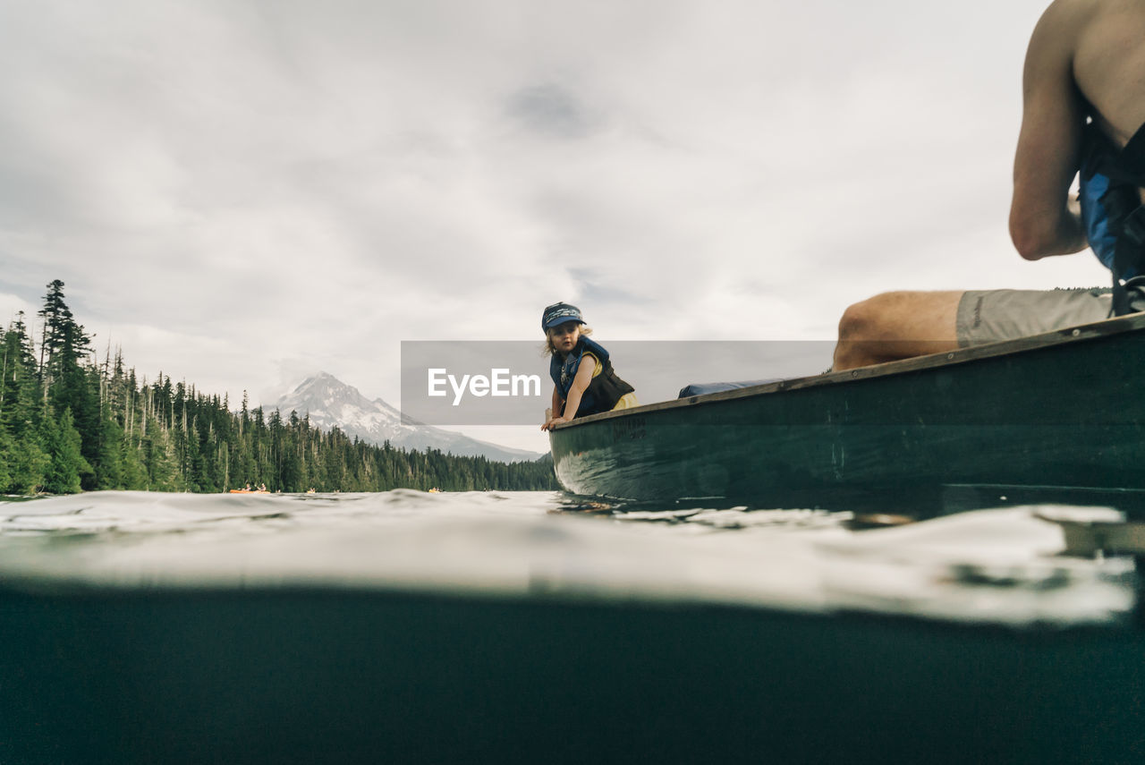 A young girl rides in a canoe with her dad on lost lake in oregon.