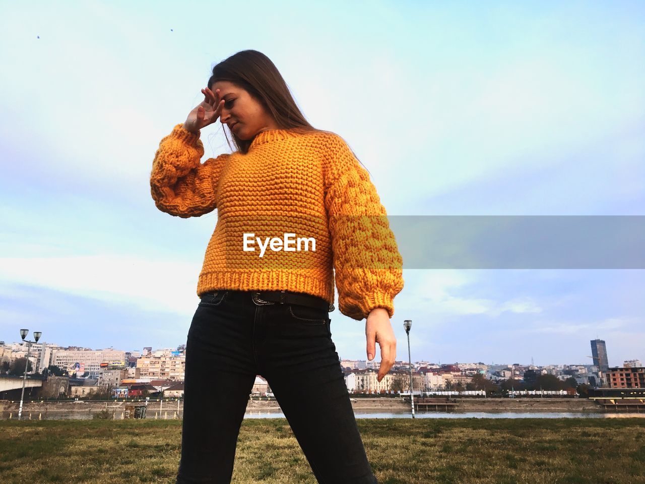 Smiling young woman in sweater against sky