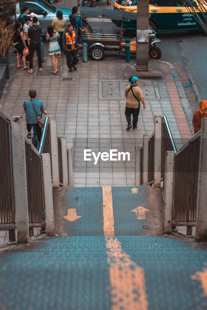 HIGH ANGLE VIEW OF PEOPLE WALKING ON COBBLESTONE STREET