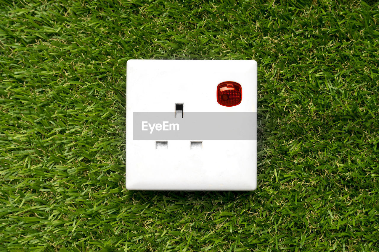 3 pin plug socket on a grass background. eco friendly electricity concept.