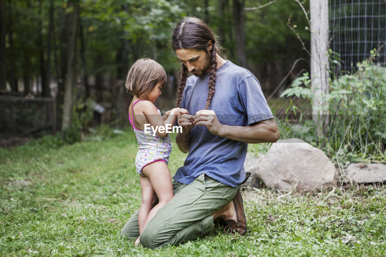 Father and daughter plaiting hair in backyard