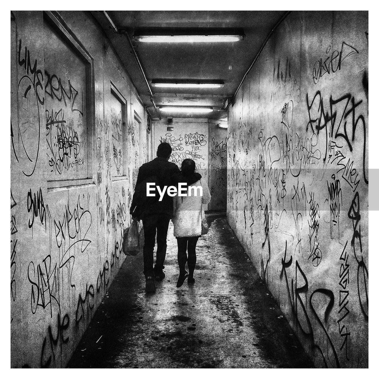 Rear view of man and woman walking arm around in building