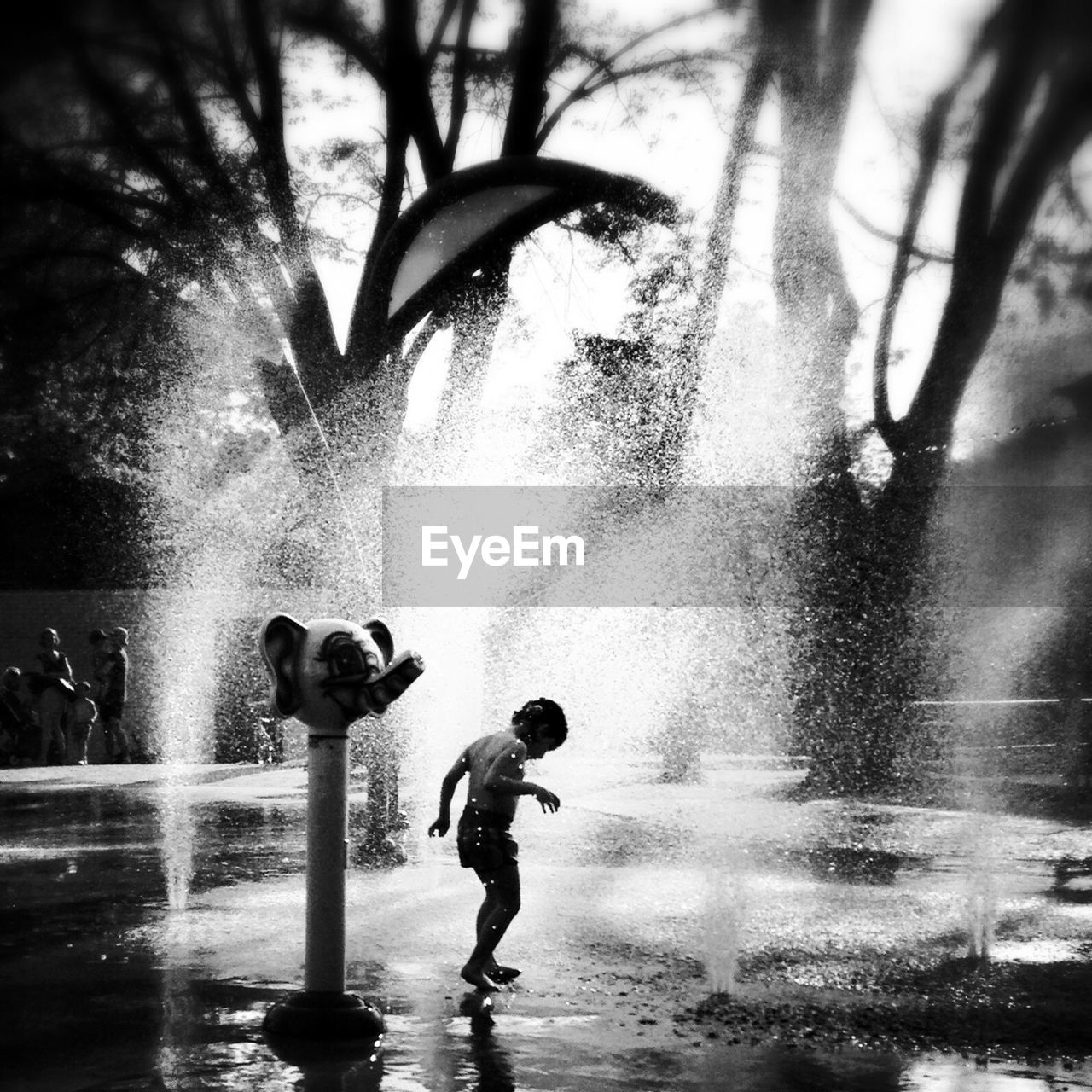 Full length of playful boy in fountain splashes