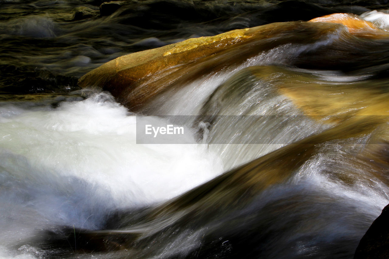 CLOSE-UP OF WATER FLOWING OVER RIVER