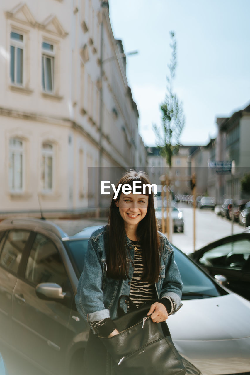 Portrait of smiling woman standing by car