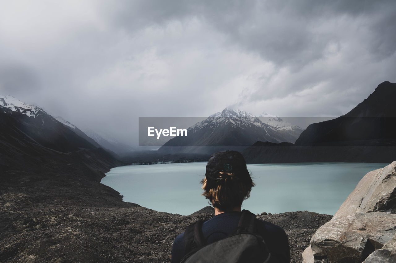 Man looking at lake against mountain range