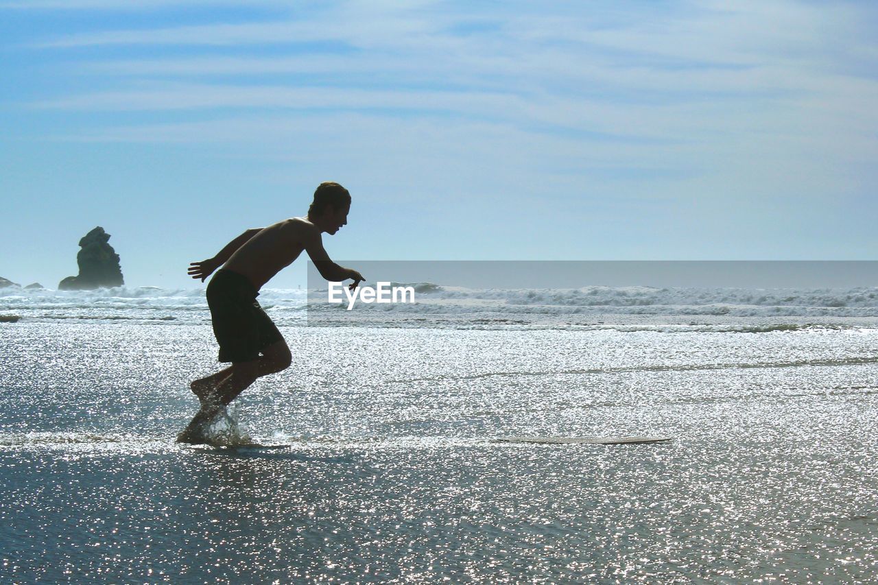 FULL LENGTH OF MAN JUMPING ON BEACH