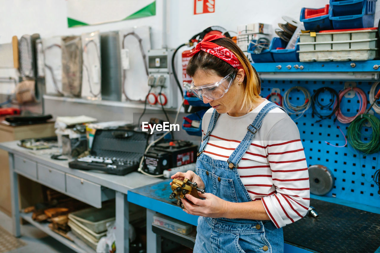 Mechanic woman checking caliper brake system in front of workbench