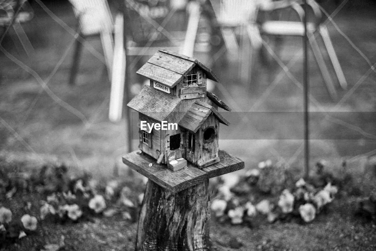 CLOSE-UP OF BIRDHOUSE ON FIELD AGAINST TREES