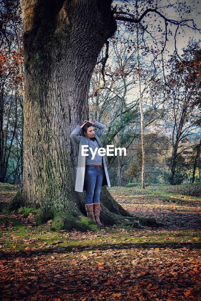 Full length of woman standing against trees in forest