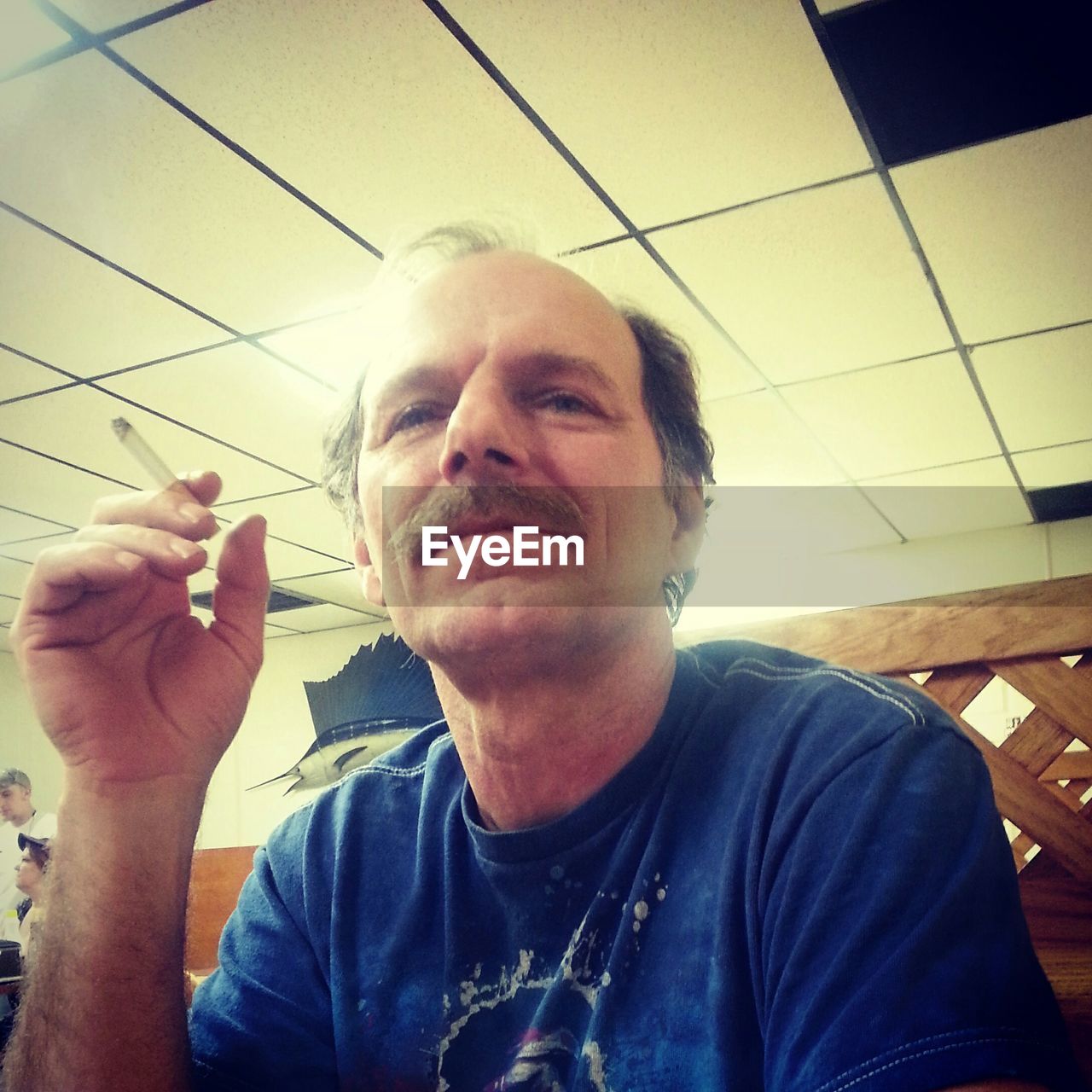 Mature man holding cigarette in restaurant