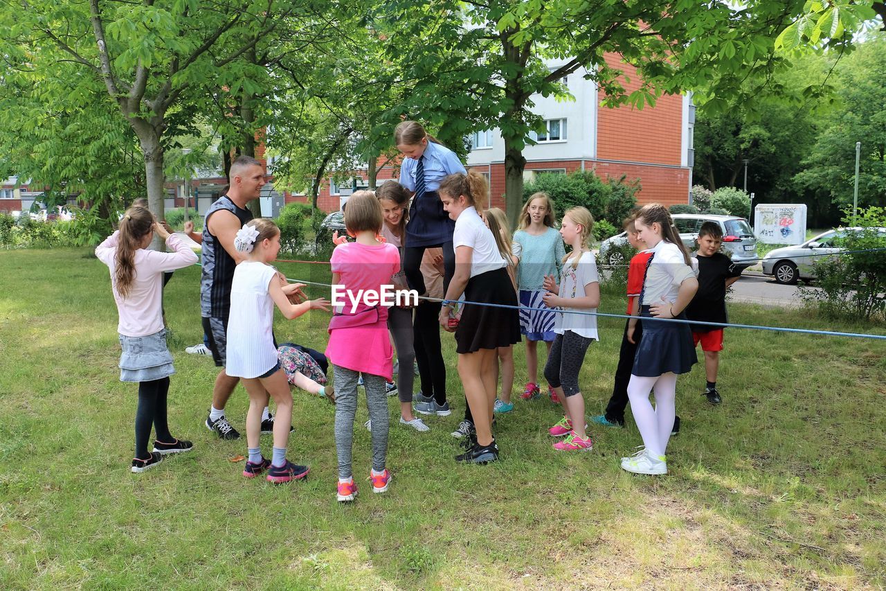 CHILDREN STANDING ON TREE TRUNK