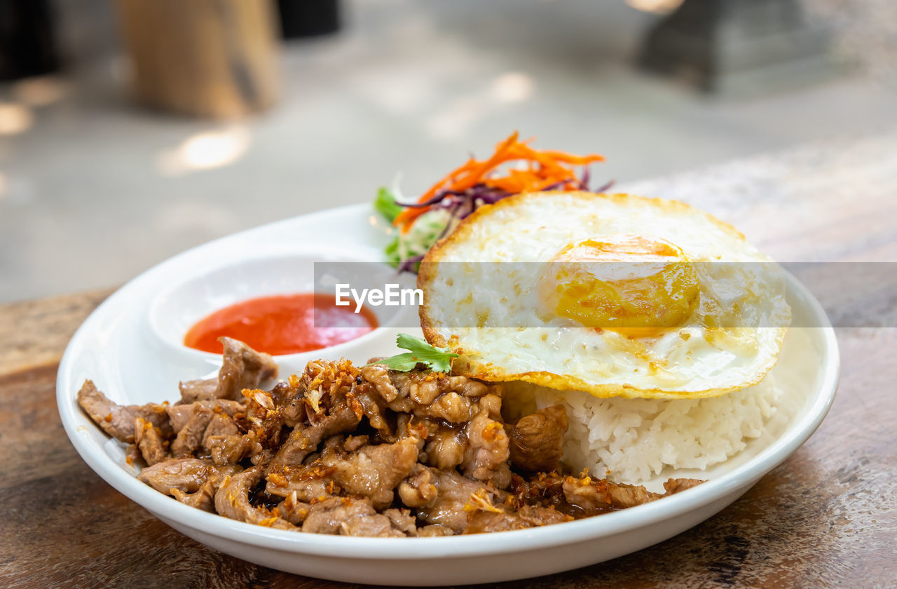 Fried pork with garlic served with jasmine rice and fired egg, native thai street food in bangkok.