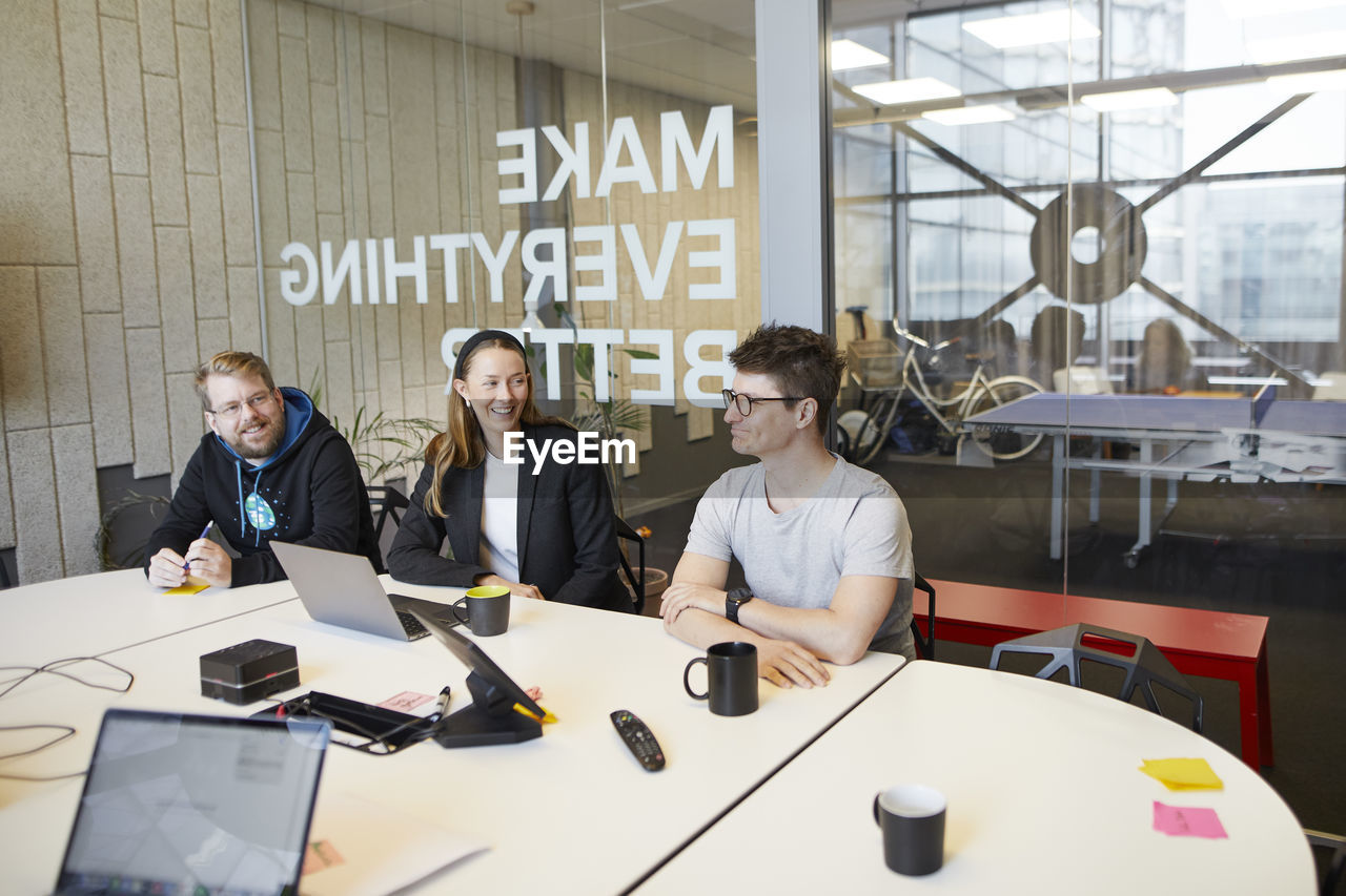 Smiling people sitting in boardroom during business meeting