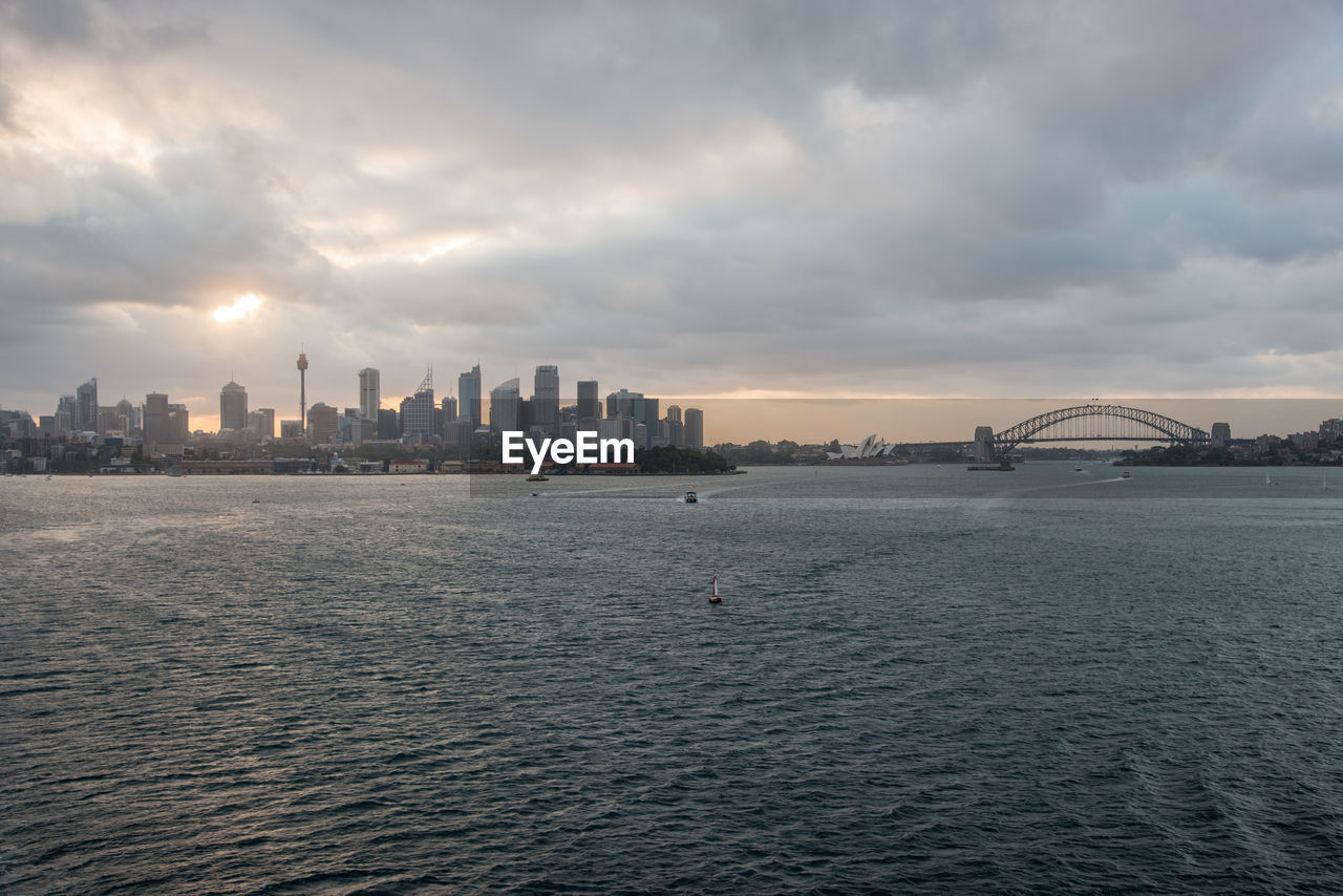 SEA AND BUILDINGS AGAINST SKY DURING SUNSET