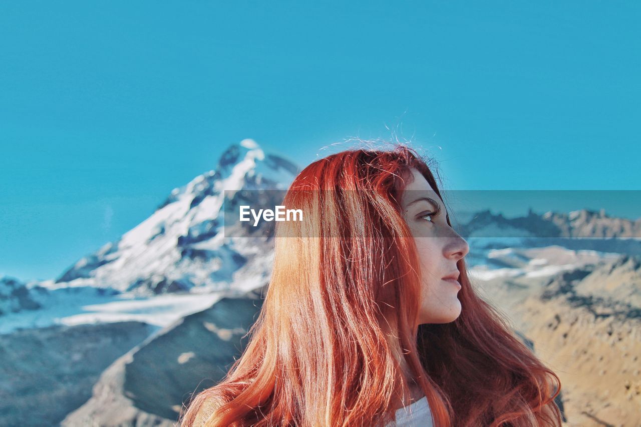 Young woman looking away against mountains in winter