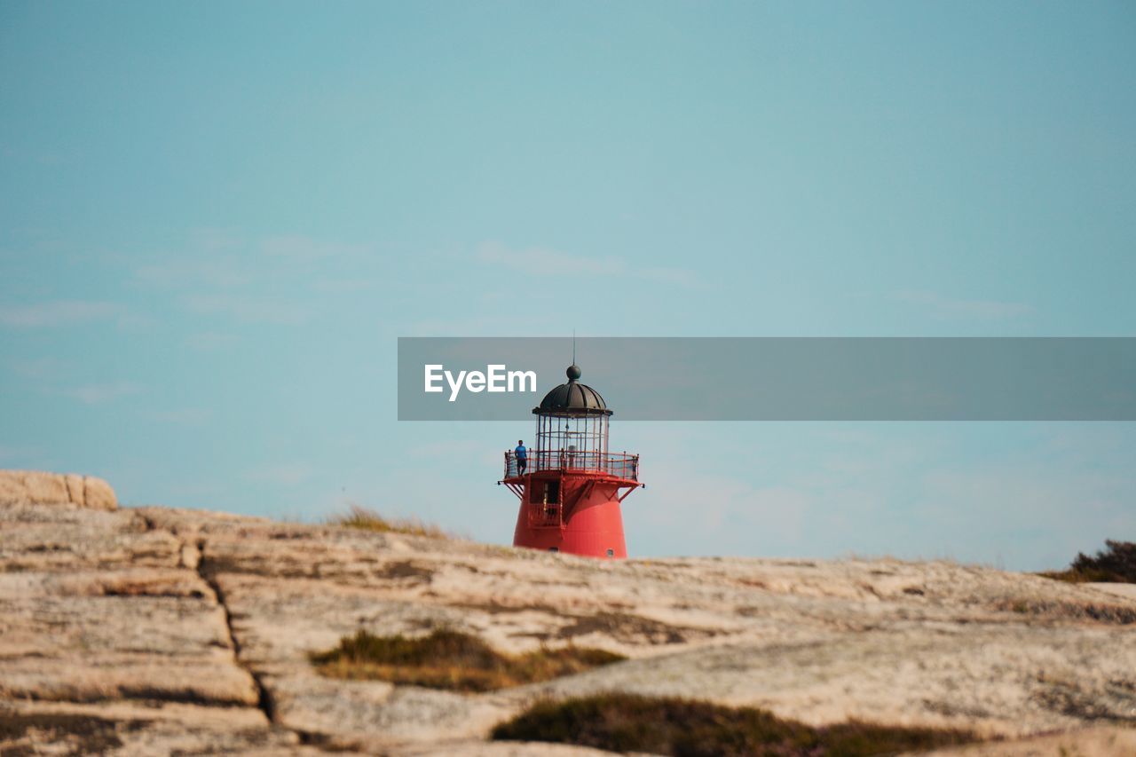 Lighthouse on rock against sky