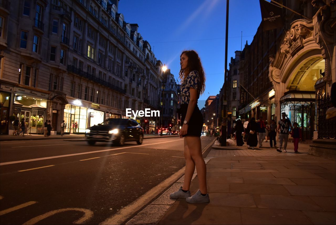 Full length of woman standing on city street at night