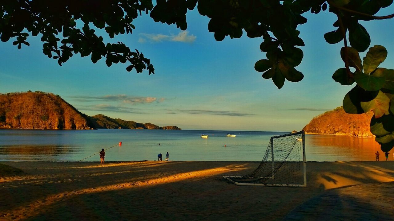 Soccer goal post on beach against sea at dusk