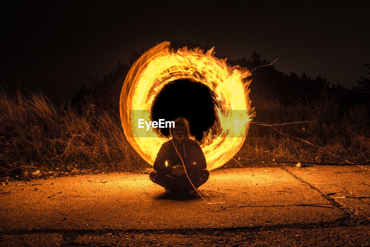 Man sitting against illuminated wire wool at night