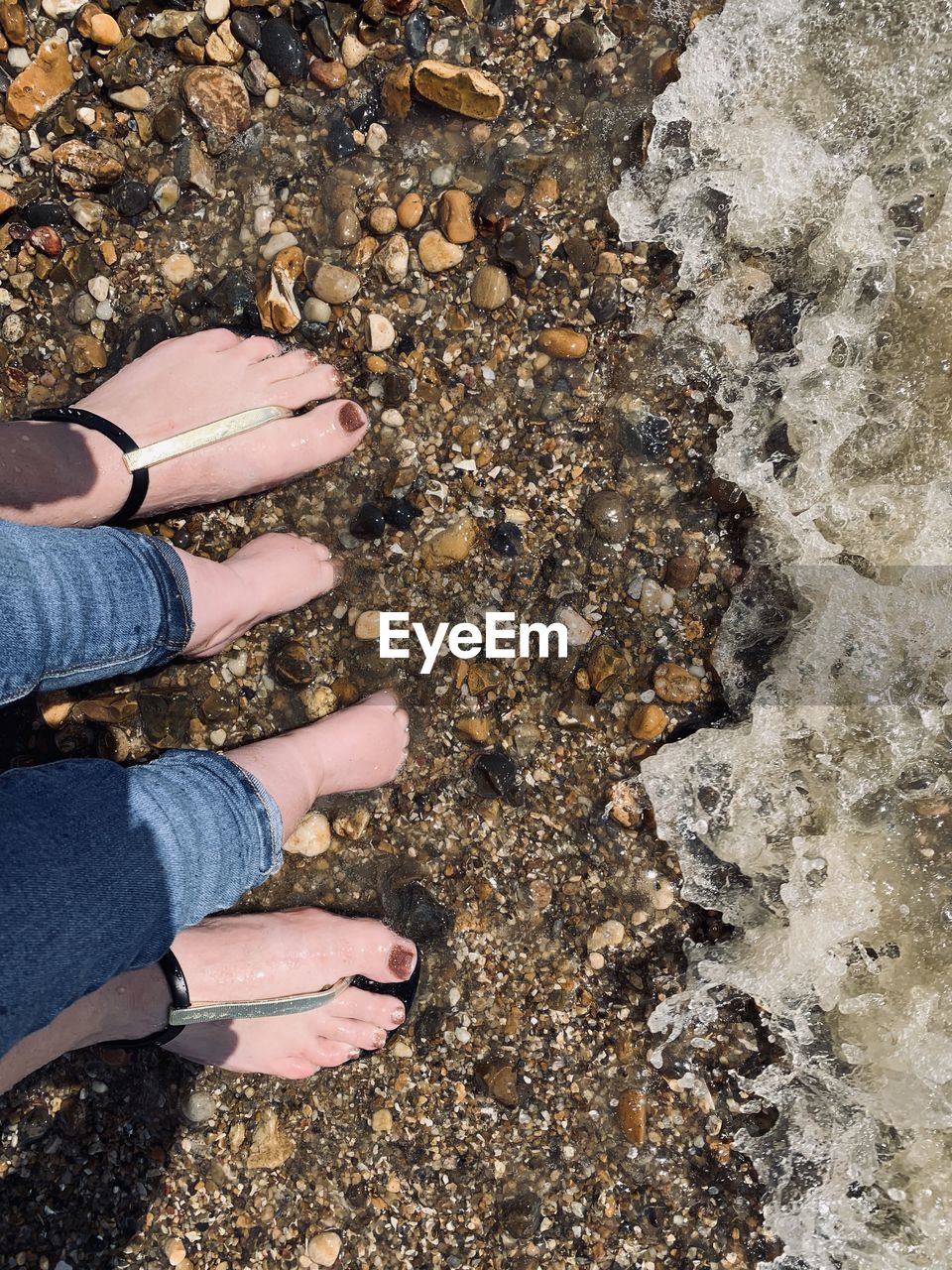 low section, human leg, high angle view, soil, shoe, standing, land, nature, one person, rock, day, beach, lifestyles, sand, leisure activity, personal perspective, directly above, outdoors, women, adult, human foot, sunlight, sandal, spring, geology, casual clothing, limb, human limb, footwear, water, barefoot, jeans, men