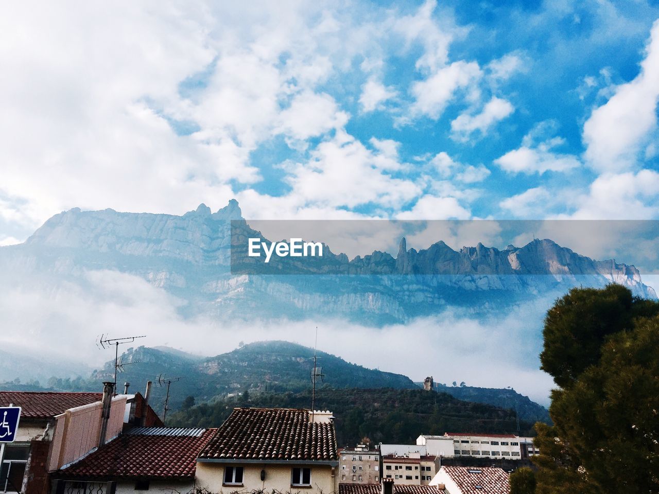 Houses on mountain against cloudy sky