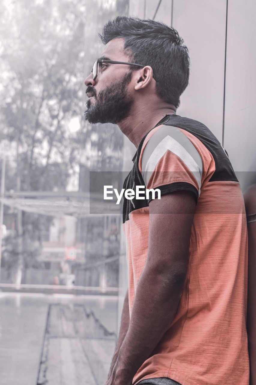 one person, adult, men, young adult, lifestyles, city, side view, architecture, beard, glasses, facial hair, casual clothing, clothing, athlete, sports, looking, waist up, photo shoot, person, city life, fashion, day, standing, black, exercising, relaxation, muscular build, outdoors, sports clothing, leisure activity, player, eyeglasses, portrait, strength, looking away, profile view, white, nature, sunglasses, stubble