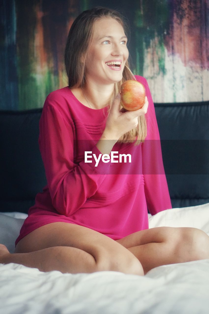 young woman using mobile phone while lying on bed