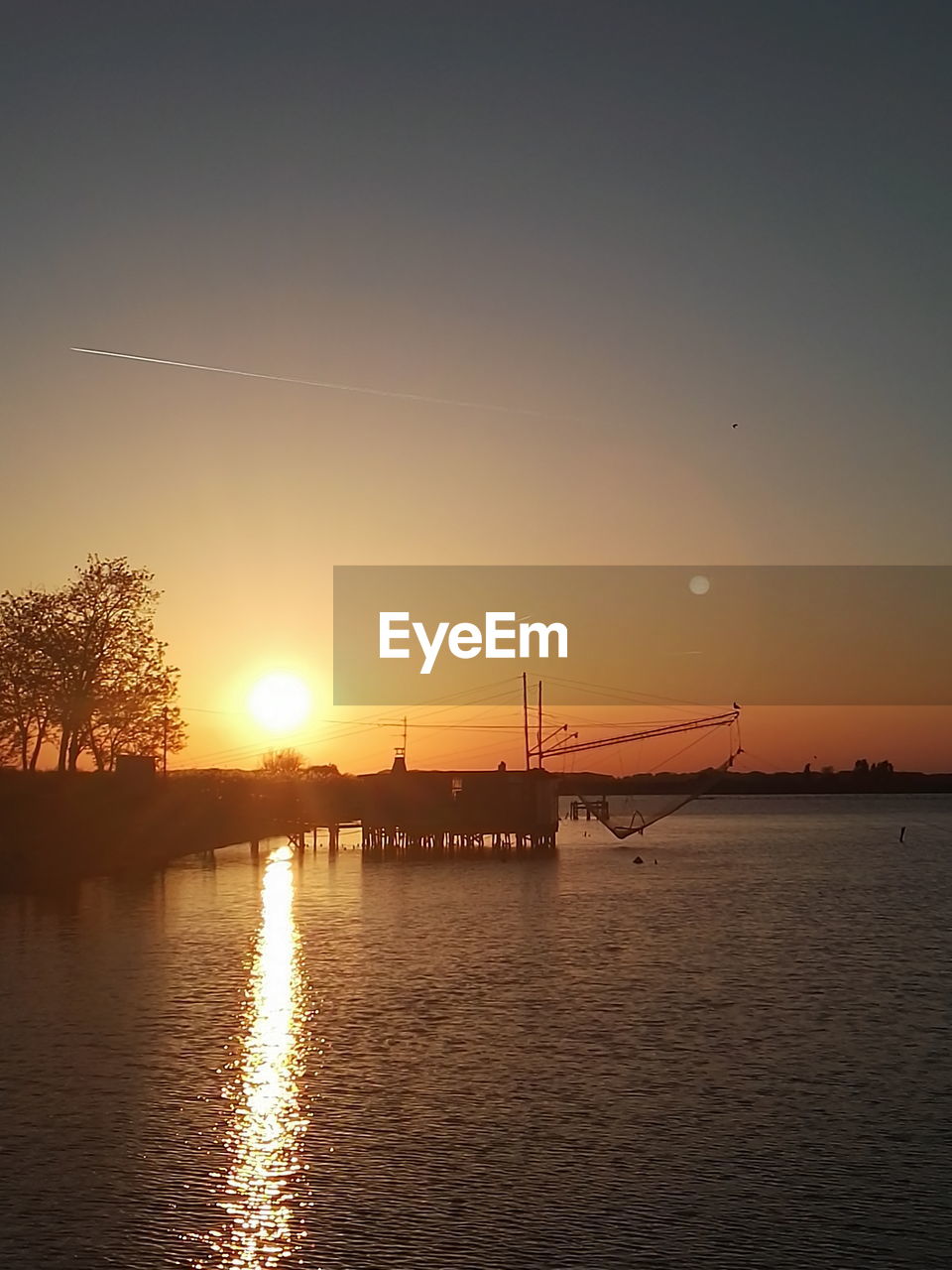 SILHOUETTE BRIDGE OVER RIVER AGAINST ORANGE SKY