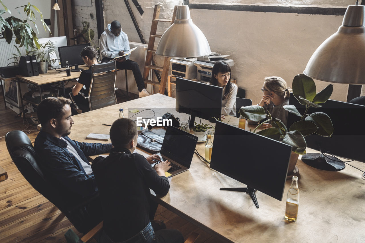 Male and female computer programmers working over desk at place of work