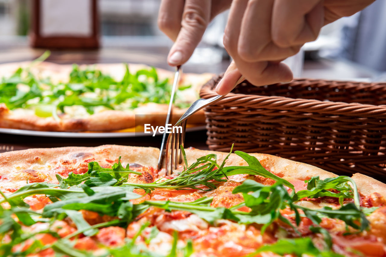 Appetizing pizza in a cafe. the visitor cuts the pizza with a knife and fork at the table.