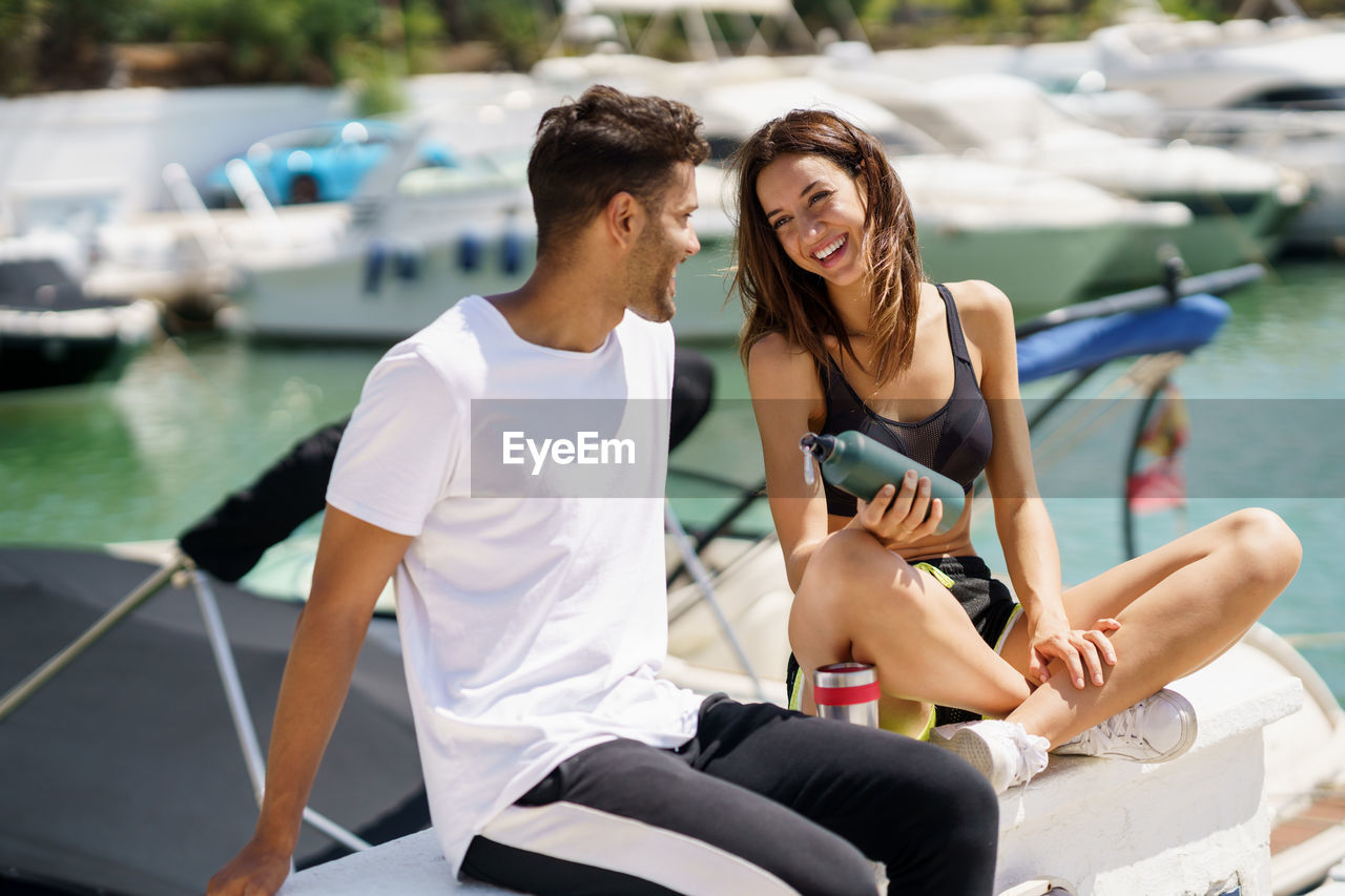 Smiling couple while sitting at harbor