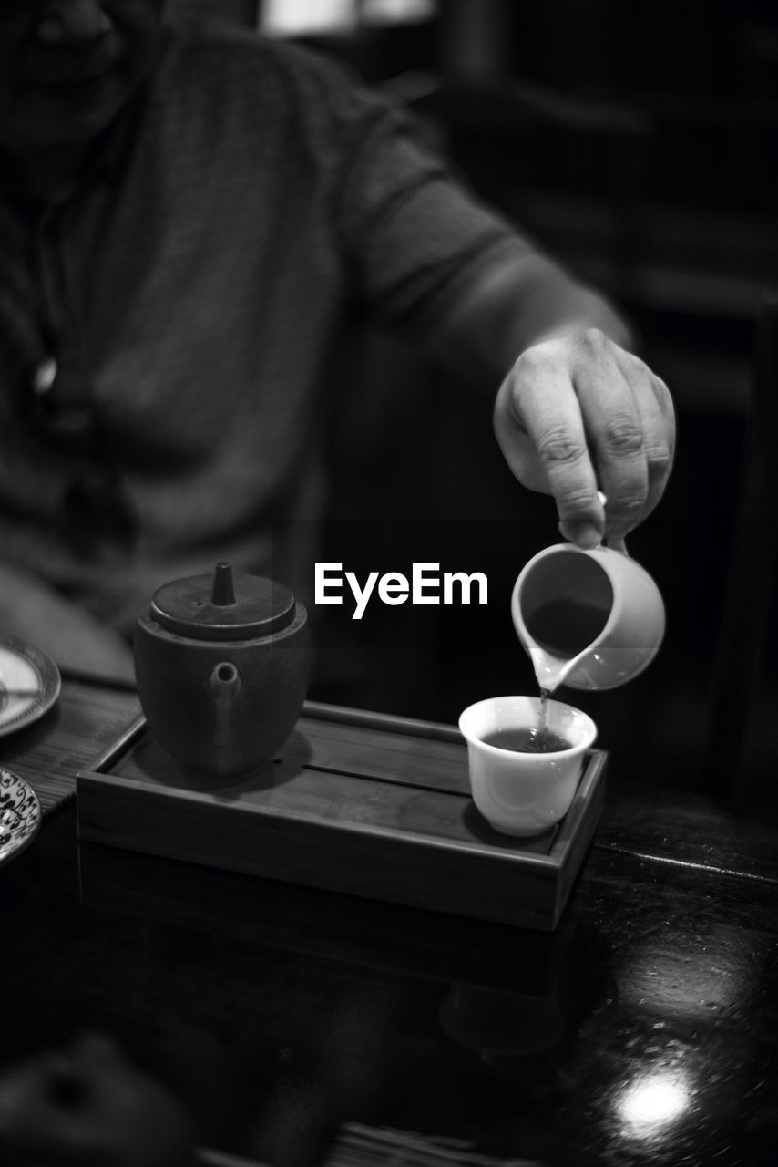 midsection of man holding coffee at table