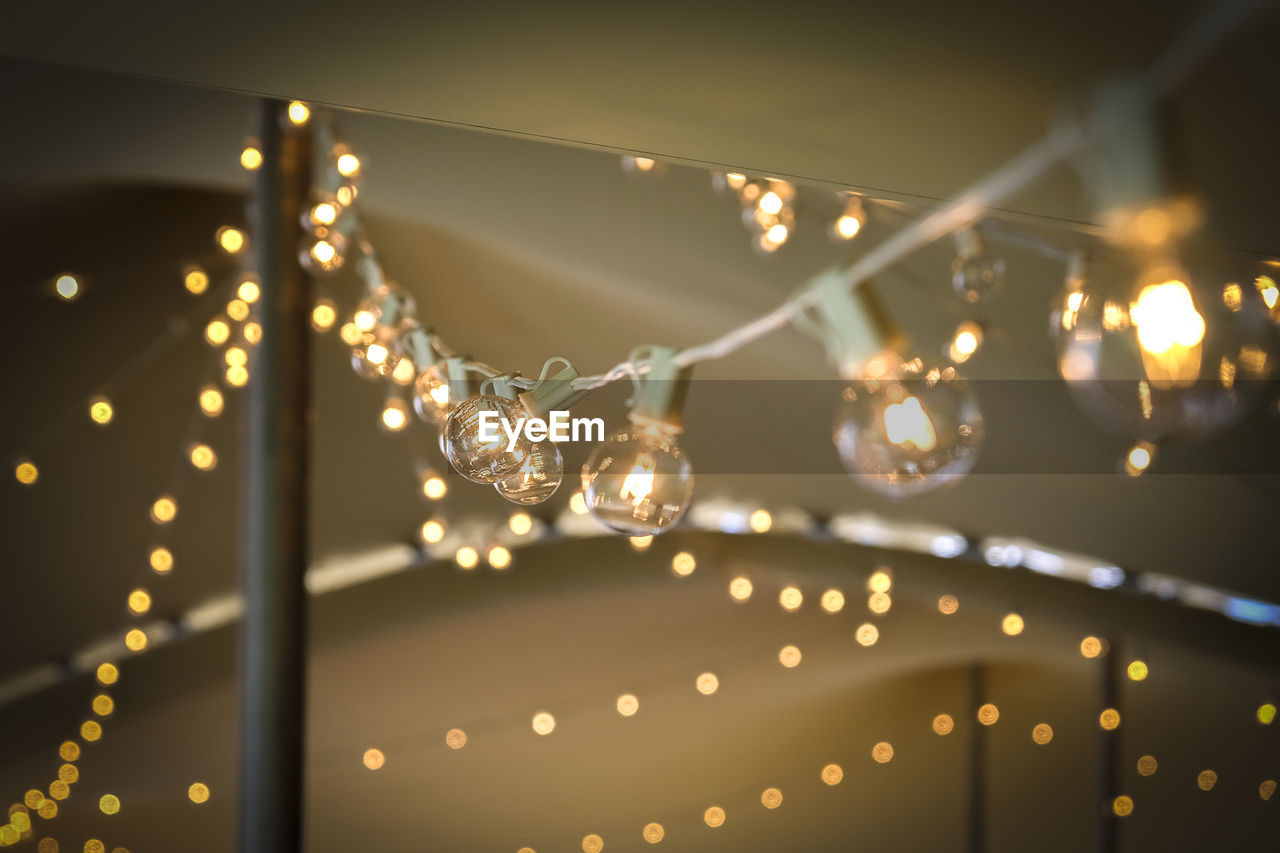 Low angle view of illuminated light bulbs on string during party