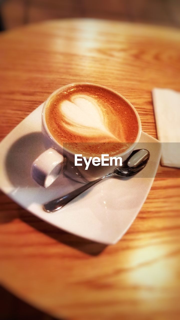 CUP OF COFFEE WITH SPOON ON TABLE