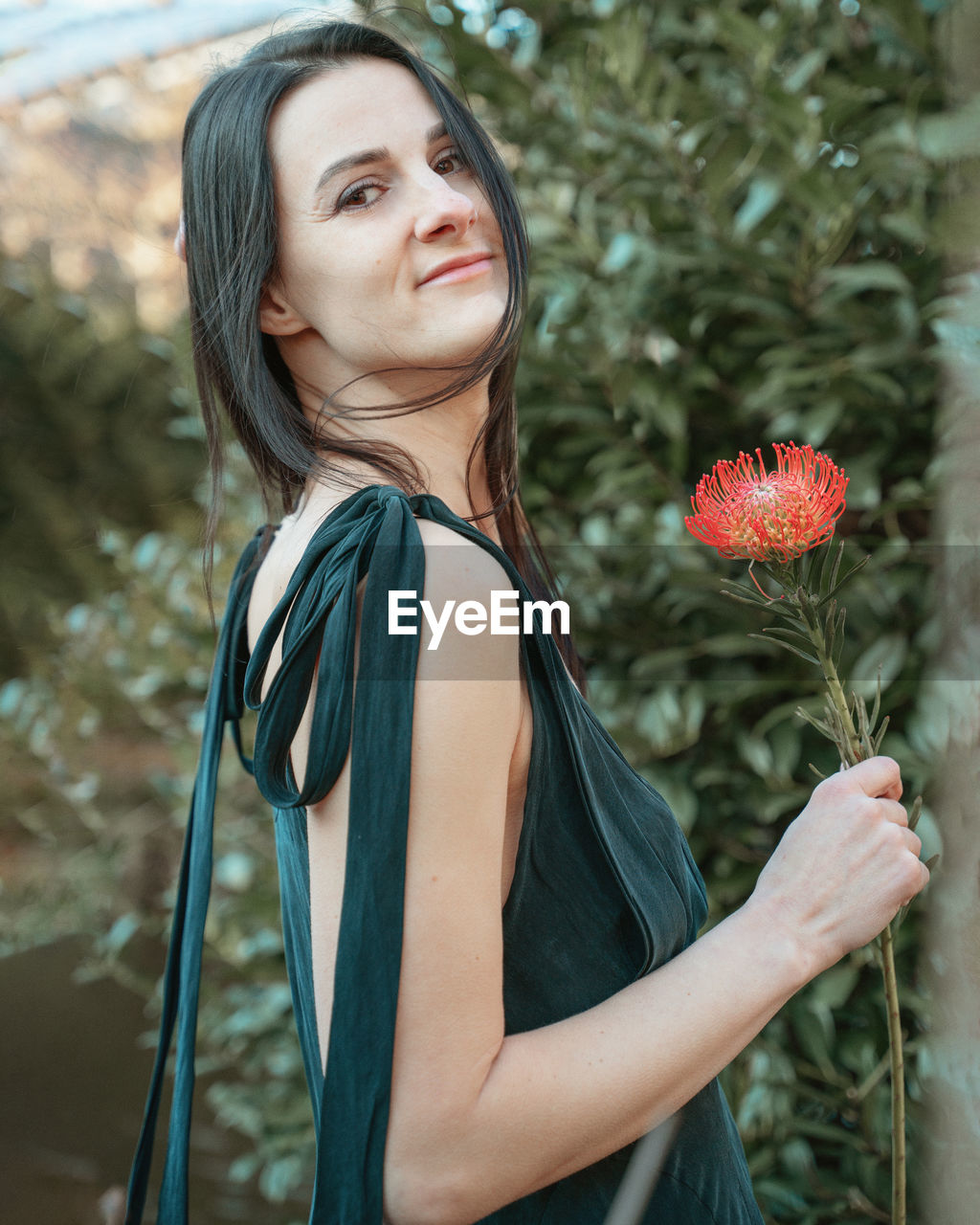 portrait of young woman standing by tree