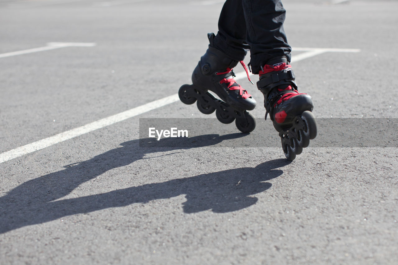 Low section of person roller skating on road