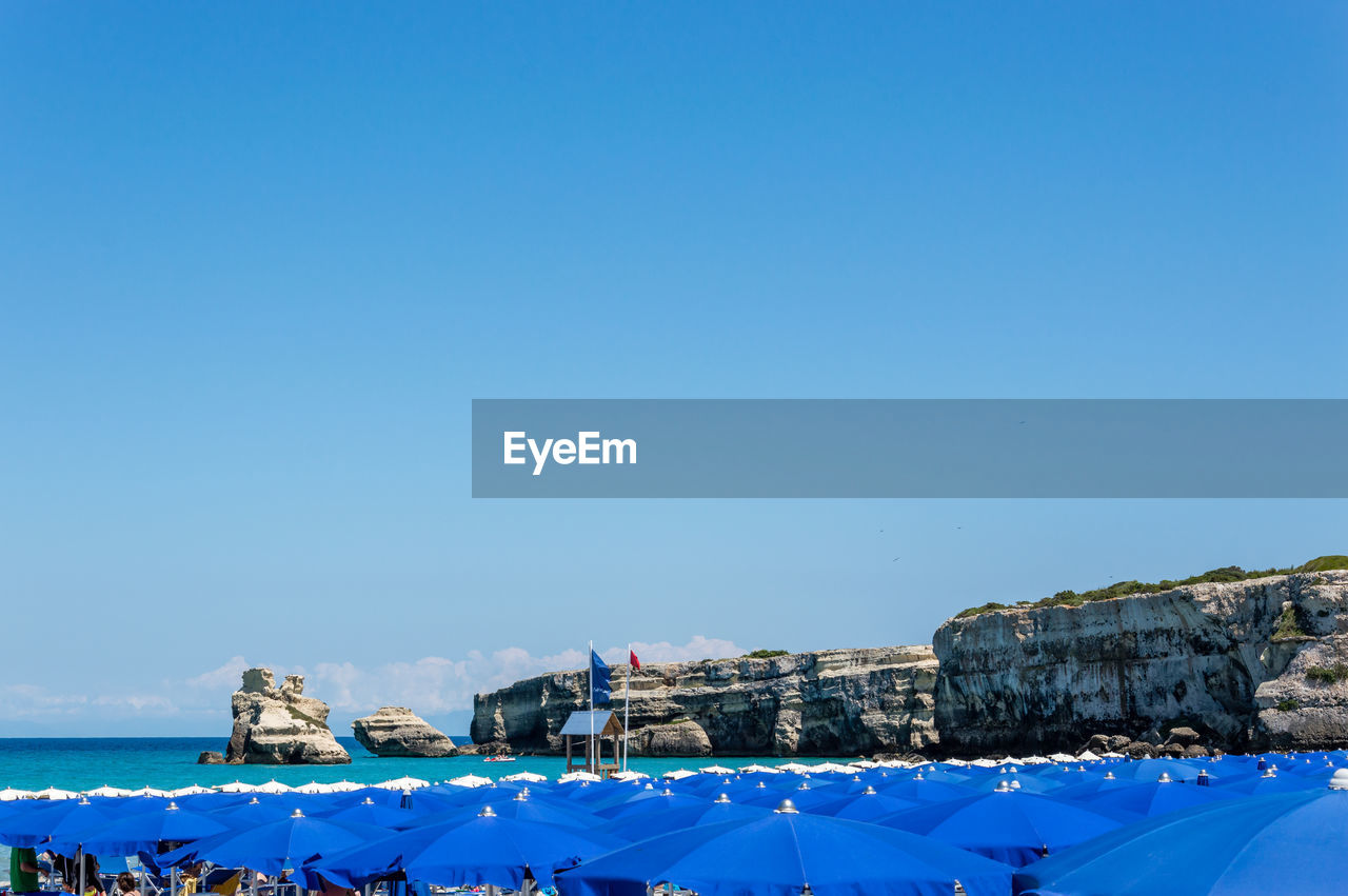 BUILDINGS BY SEA AGAINST CLEAR BLUE SKY