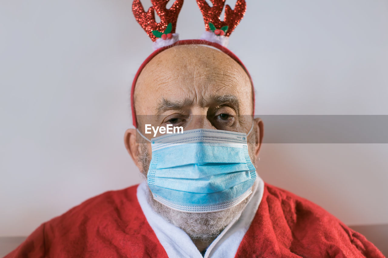 Portrait of senior man wearing mask sitting at home