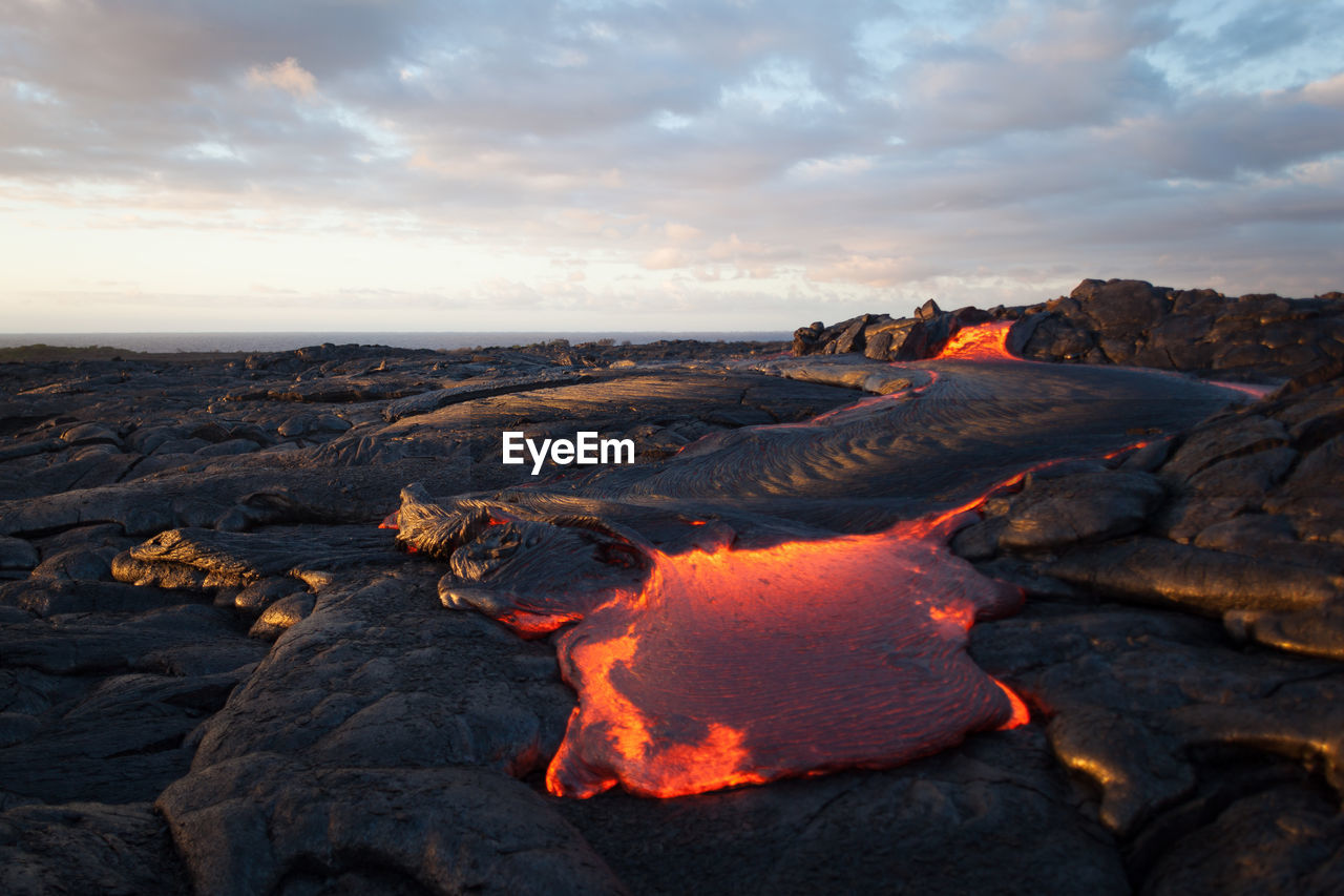 Scenic view of volcano erupting against sky during sunset