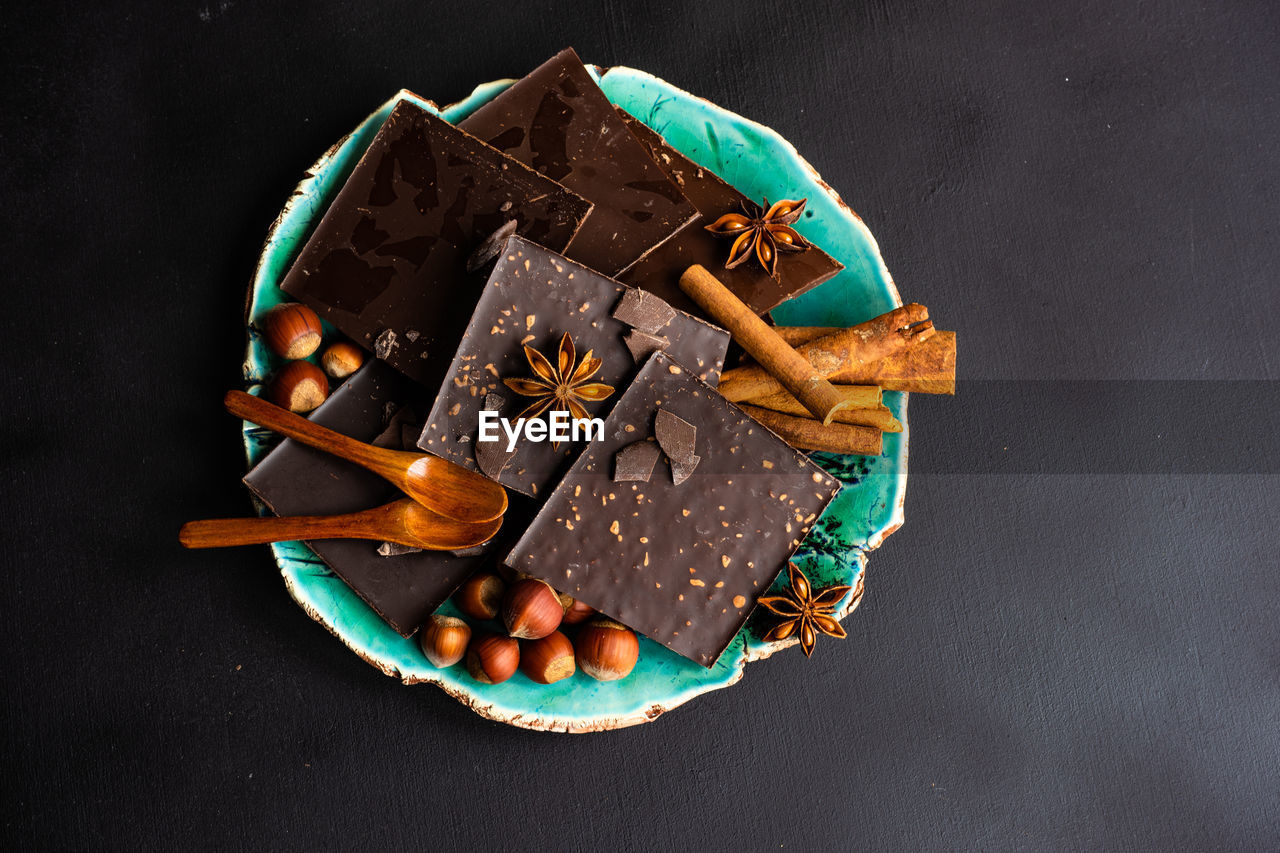 High angle view of chocolate bars with spices and nuts in plate on table