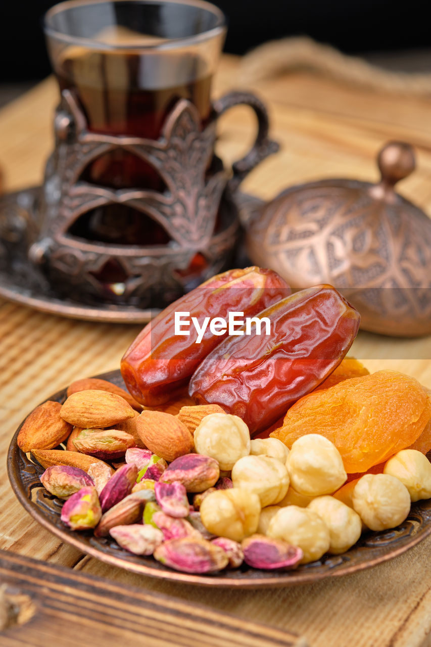 Dates, dried apricots, nut mix and tea in traditional arabian style brass holder.  ramadan kareem