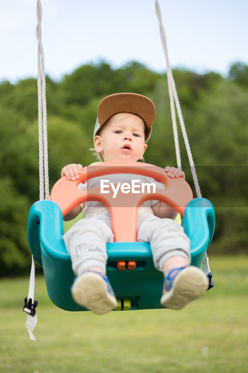 full length of boy swinging on field