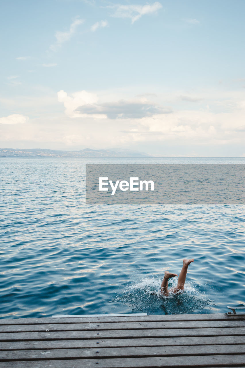 A person's feet sticking out of the water as they dive in off a dock