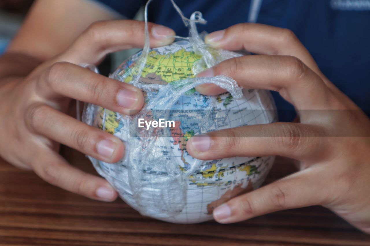 Midsection of woman holding globe in plastic on table