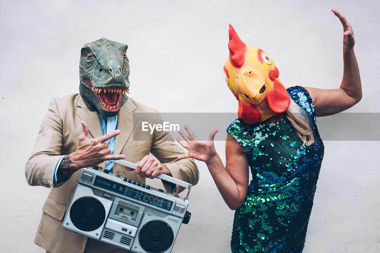 People in mask dancing against wall