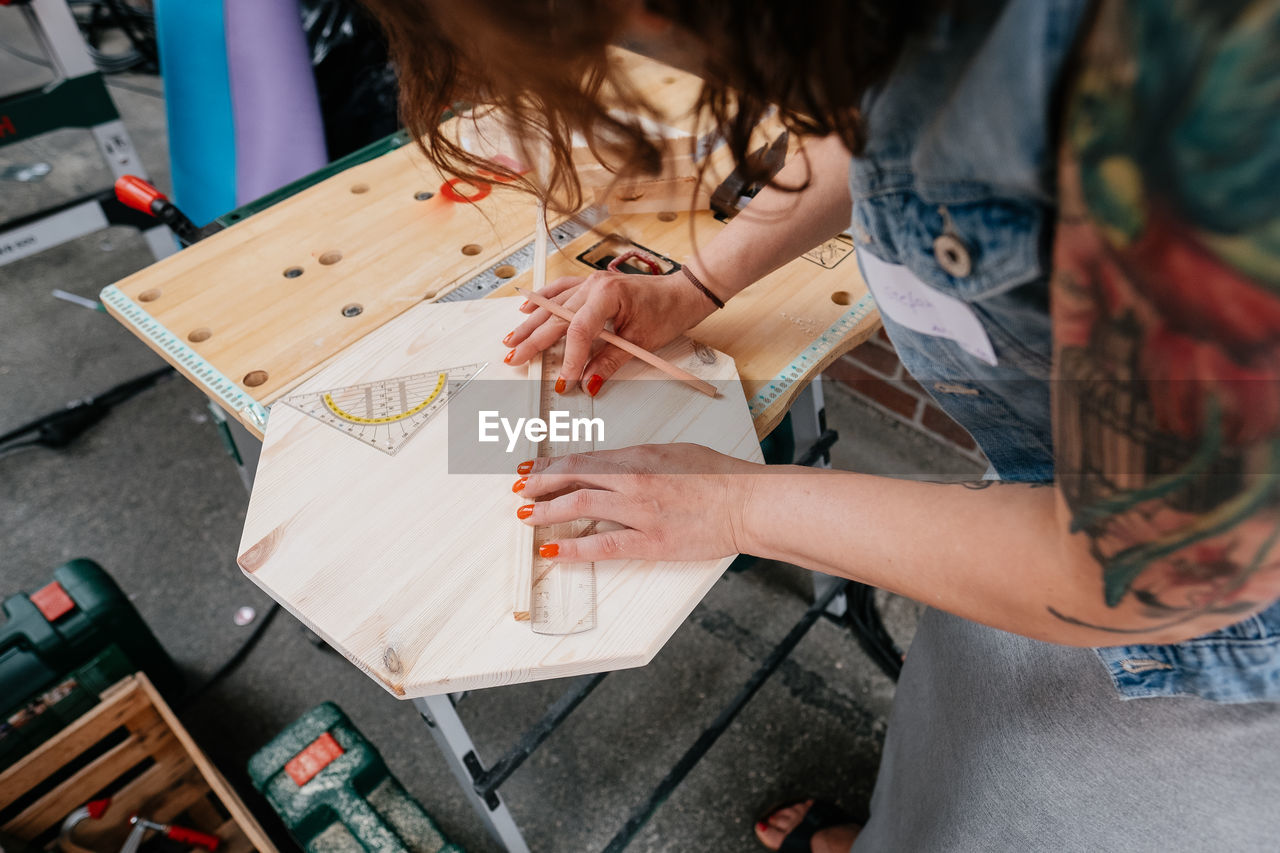 High angle view of woman measuring wood in workshop