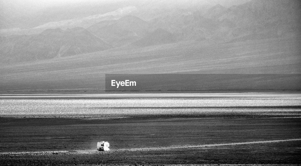 REAR VIEW OF PEOPLE LOOKING AT SEA AGAINST SKY