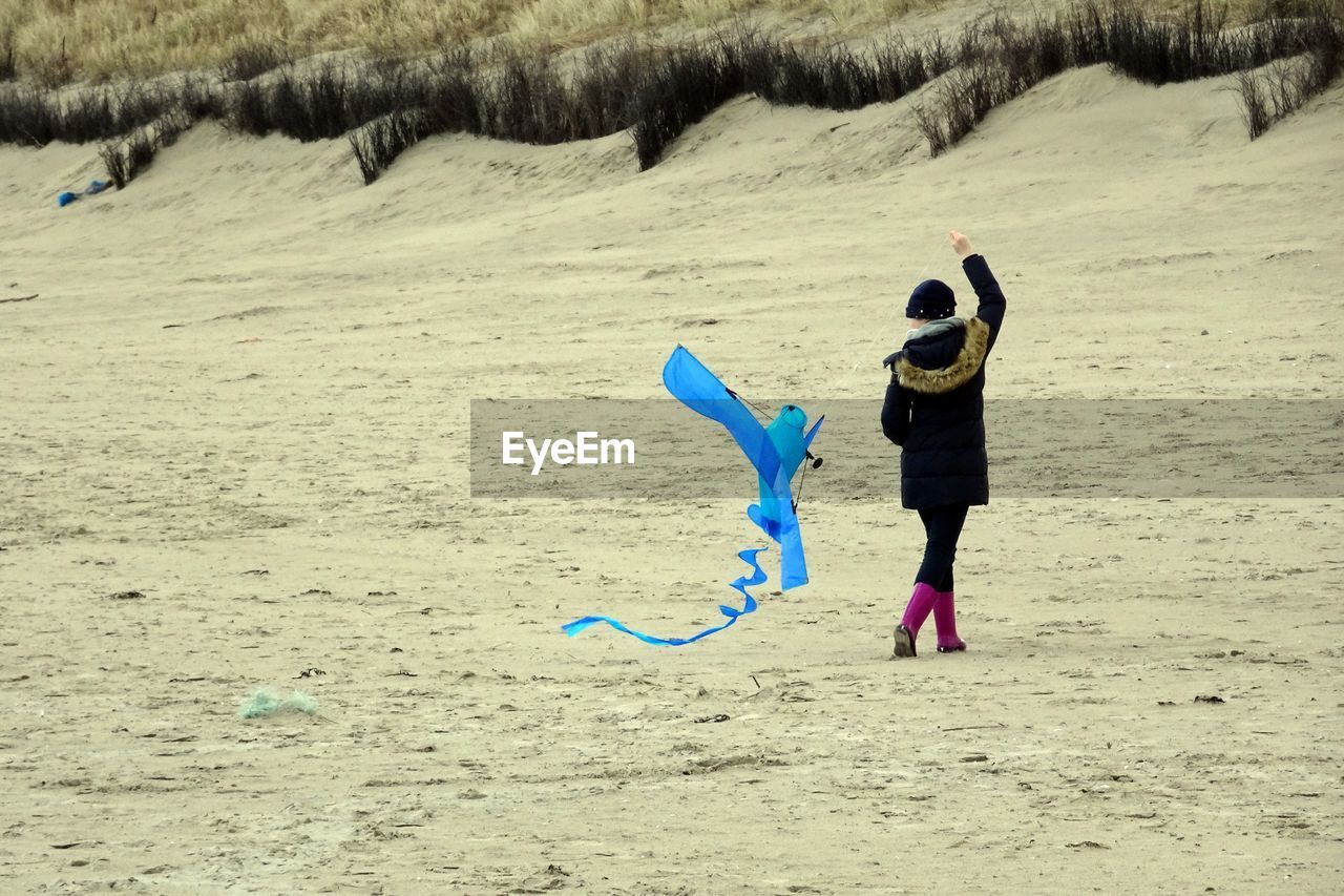 Rear view of girl with kite walking on beach