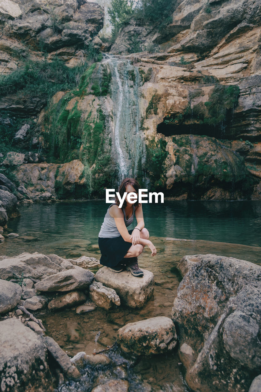 Woman next to a waterfall looking at camera